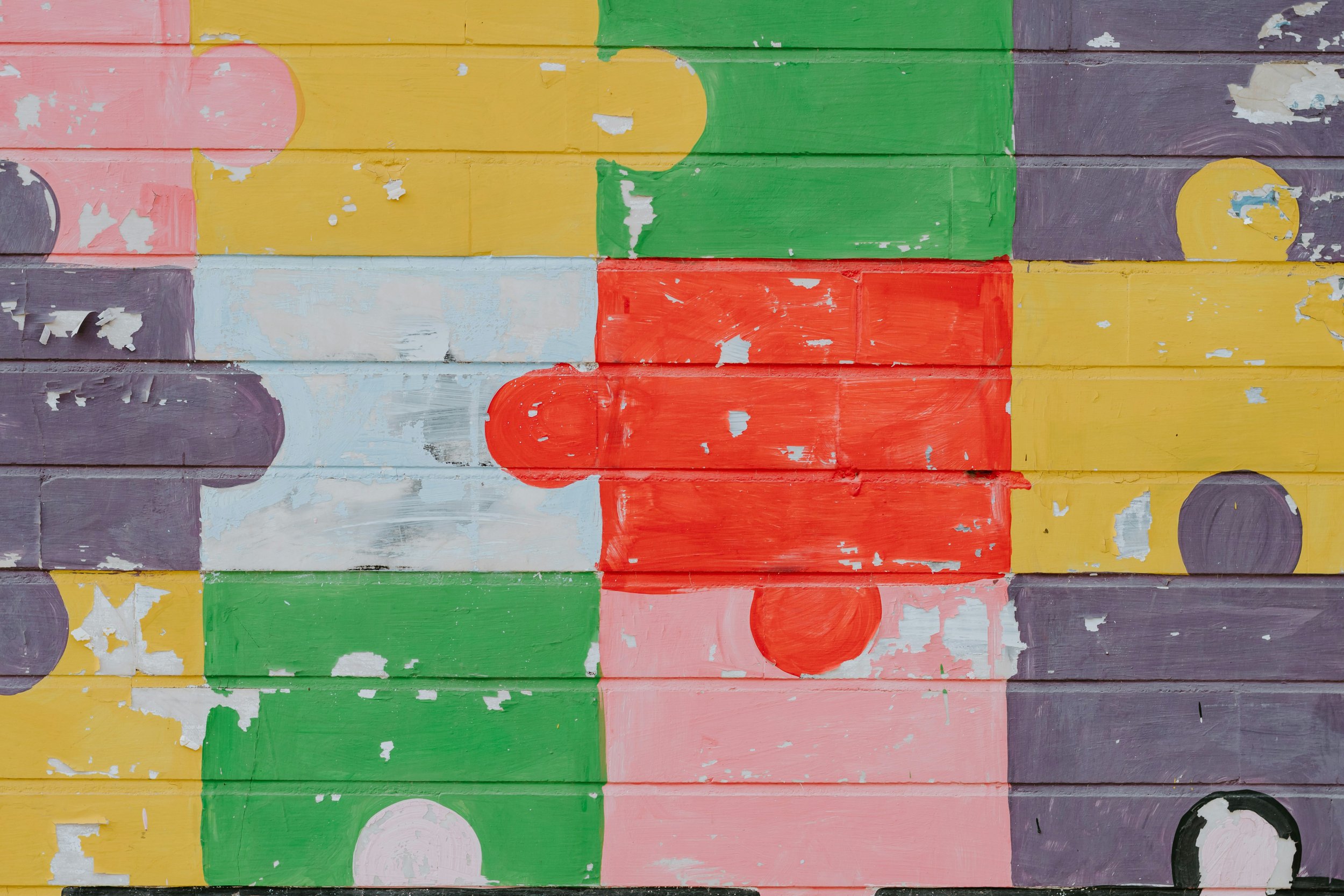 Colorful mural with painted puzzle pieces in red, green, yellow, pink, and purple.